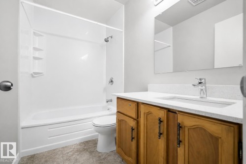 Bathroom with a wood-finish vanity, white countertop, integrated sink, and chrome fixtures - 3173 139 Avenue Nw, Edmonton, AB 