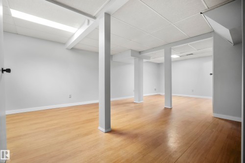 Expansive room featuring wood-finish flooring, drop ceiling with integrated lighting, and neutral wall paint - 3173 139 Avenue Nw, Edmonton, AB 