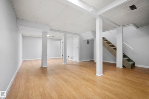 Finished lower level featuring wood-finish flooring, drop ceiling panels, and a carpeted staircase - 3173 139 Avenue Nw, Edmonton, AB 
