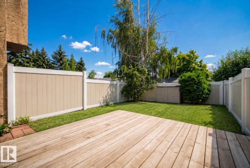 Expansive wood deck with a manicured lawn, established landscaping, and privacy fencing - 3173 139 Avenue Nw, Edmonton, AB 