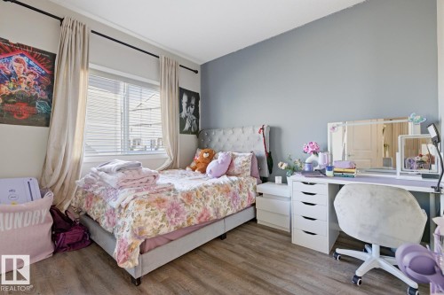 Room featuring wood-finish flooring, a window with horizontal blinds, and a built-in closet door - #155 1818 Rutherford Rd Sw, Edmonton, AB 