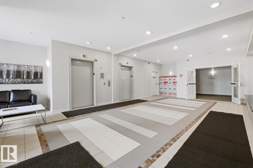 Building entryway featuring dual elevators, recessed lighting, tile flooring, and double entry doors - #155 1818 Rutherford Rd Sw, Edmonton, AB 