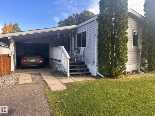 Carport parking, exterior siding, front porch with railing, concrete walkway, and gravel driveway - 8 The Parkway Northwest, Edmonton, AB 
