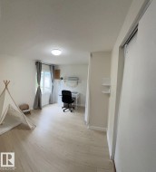 Spacious room featuring light wood-finish flooring, abundant natural light from a double window, and a built-in sliding panel door - 