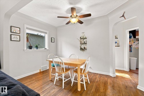 Wood-finish flooring with a ceiling fan light fixture and a white trim window - 10943 72 Avenue Nw, Edmonton, AB 