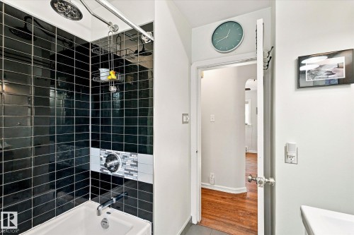 Bathtub with a black subway tile surround, mosaic accent tile, and a dual shower head system - 10943 72 Avenue Nw, Edmonton, AB 