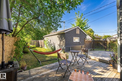 Expansive backyard featuring a wood deck, manicured lawn, and mature trees - 10943 72 Avenue Nw, Edmonton, AB 