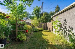 Grassed side yard featuring a wood fence, stucco exterior, and mature greenery - 