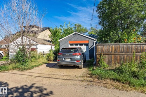 Detached garage with a roll-up door, accompanied by a wood-panel fence - 10943 72 Avenue Nw, Edmonton, AB 