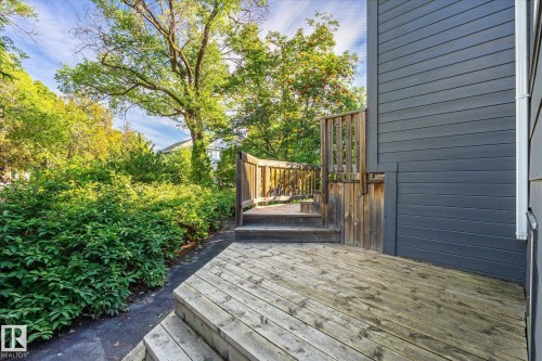 Expansive wooden deck with multi-level design and wood railing, surrounded by lush landscaping and mature trees - 10943 72 Avenue Nw, Edmonton, AB 