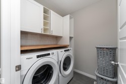 Built-in white cabinetry, open shelving, wood-finish countertop, and a tiled backsplash - 