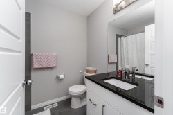 White vanity with dark countertop, undermount sink, and brushed nickel hardware - 