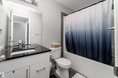 White vanity with a black countertop, undermount sink, and chrome faucet - 20247 16 Avenue Nw, Edmonton, AB 