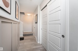 Wood-finish flooring throughout, featuring a wainscoting accent wall and modern white sliding panel doors - 