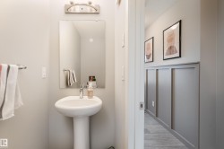 Pedestal sink with chrome faucet, rectangular mirror, and a wall-mounted light fixture - 