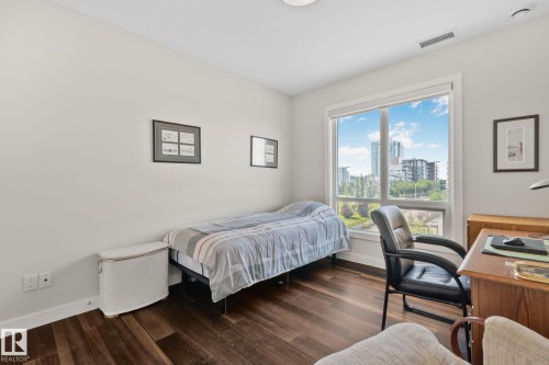 Expansive window with roller shade, dark wood-finish flooring, recessed lighting, and light-colored walls - #404 2755 109 St Nw, Edmonton, AB 