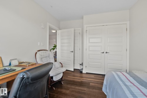 Wood-finish flooring, white paneled doors, and a built-in closet with white paneled doors - #404 2755 109 St Nw, Edmonton, AB 