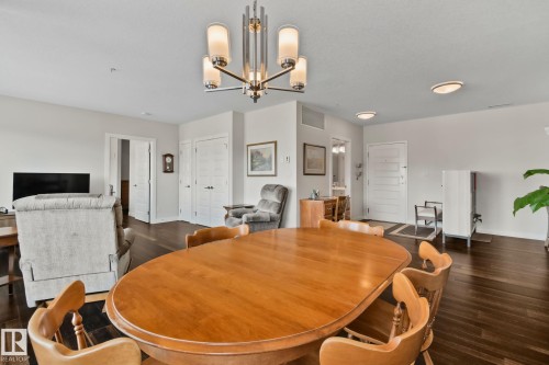 Hardwood-finish flooring, recessed lighting, and a modern chandelier illuminate this open space - #404 2755 109 St Nw, Edmonton, AB 