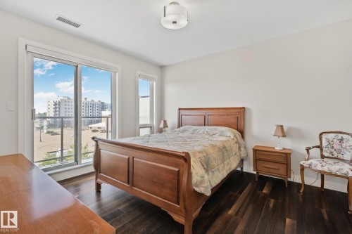 Hardwood flooring, sliding glass door with balcony access, additional window, ceiling-mounted light fixture, and light wall finishes - #404 2755 109 St Nw, Edmonton, AB 