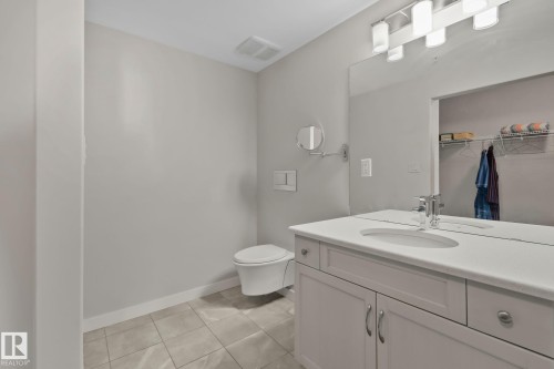 Floating vanity with an integrated sink, polished chrome faucet, and expansive mirror - #404 2755 109 St Nw, Edmonton, AB 