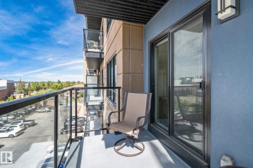 Balcony with clear glass railings, a black metal frame, and an exterior wall sconce - #404 2755 109 St Nw, Edmonton, AB 