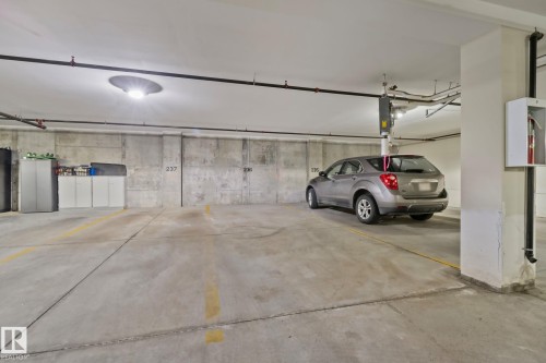 Concrete floor with painted yellow parking lines, concrete walls, overhead lighting, and exposed ceiling pipes - #404 2755 109 St Nw, Edmonton, AB 