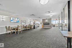 Spacious common area featuring patterned carpet flooring, a wall-mounted fireplace, recessed lighting, and large windows - 