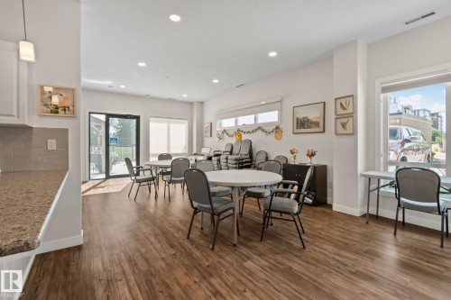 Wood-finish flooring throughout, complemented by a sliding glass door and multiple windows, providing ample natural light - #404 2755 109 St Nw, Edmonton, AB 
