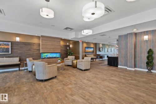 Spacious common area featuring wood-finish flooring, a built-in aquarium, and modern pendant lighting - #404 2755 109 St Nw, Edmonton, AB 