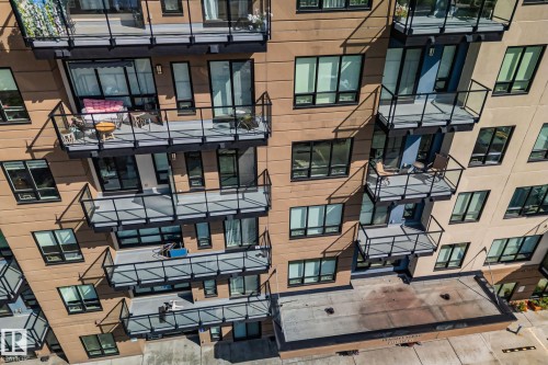 Contemporary building facade with multiple balconies featuring glass railings and dark trim - #404 2755 109 St Nw, Edmonton, AB 