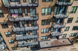 Contemporary building facade with multiple balconies featuring glass railings and dark trim - 