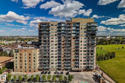 Modern high-rise residential building with multiple balconies and a large adjacent green space - #404 2755 109 St Nw, Edmonton, AB 