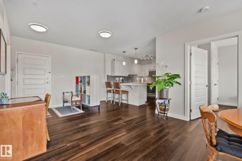 Open-concept layout featuring dark wood-finish flooring, white flat-panel cabinetry, a kitchen island with seating, and recessed lighting - #404 2755 109 St Nw, Edmonton, AB 
