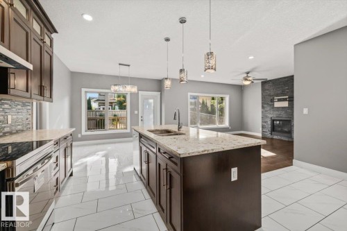 Kitchen featuring an island with a sink, pendant lighting, and dark wood cabinetry - 1090 Armitage Crescent Sw, Edmonton, AB 