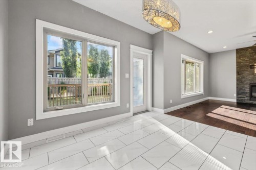 White tile flooring, large windows, French door, dark wood-finish flooring, and a stone-clad fireplace - 1090 Armitage Crescent Sw, Edmonton, AB 