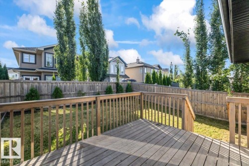 Expansive composite deck featuring wood-finish decking with matching railings, offering multiple entertaining zones across the backyard - 1090 Armitage Crescent Sw, Edmonton, AB 