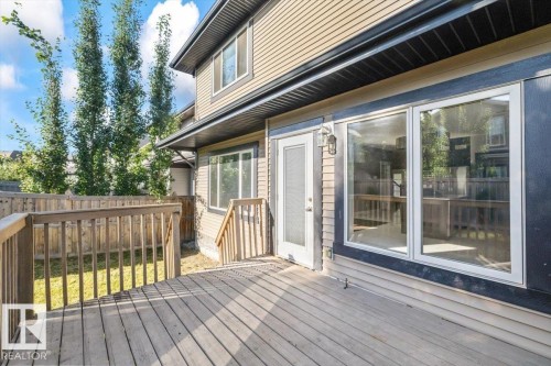 Expansive wood-finish deck with railing, a glass-panel door, and large windows - 1090 Armitage Crescent Sw, Edmonton, AB 