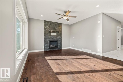 Spacious room with wood-finish flooring, a stone-clad fireplace, and recessed lighting - 1090 Armitage Crescent Sw, Edmonton, AB 