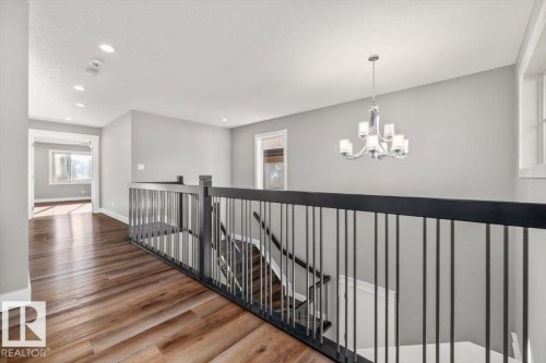 Wood-finish flooring throughout, modern baluster railing, recessed lighting, and a contemporary chandelier - 1090 Armitage Crescent Sw, Edmonton, AB 