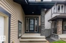 Entryway featuring a stacked stone pillar, concrete steps, and a dark-framed glass paneled door - 1090 Armitage Crescent Sw, Edmonton, AB 