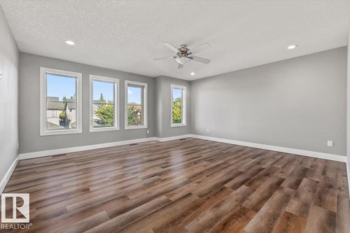 Expansive room featuring wood-finish flooring, recessed lighting, a ceiling fan, and multiple windows - 1090 Armitage Crescent Sw, Edmonton, AB 