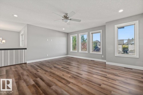 Spacious room featuring wood-finish flooring, multiple windows, recessed lighting, and a ceiling fan - 1090 Armitage Crescent Sw, Edmonton, AB 