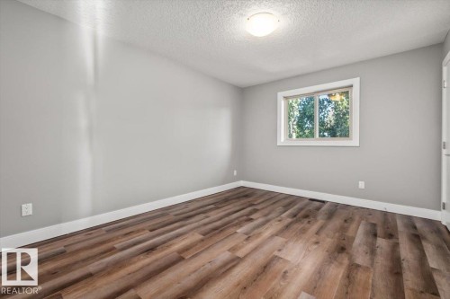 Wood-finish flooring with white trim, light gray walls, and a white ceiling with a flush-mount light fixture - 1090 Armitage Crescent Sw, Edmonton, AB 