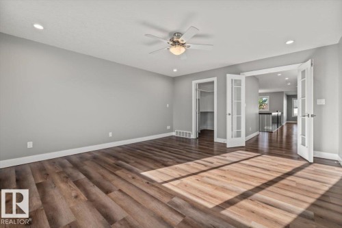 Wood-finish flooring, recessed lighting, ceiling fan with integrated light, and French doors - 1090 Armitage Crescent Sw, Edmonton, AB 