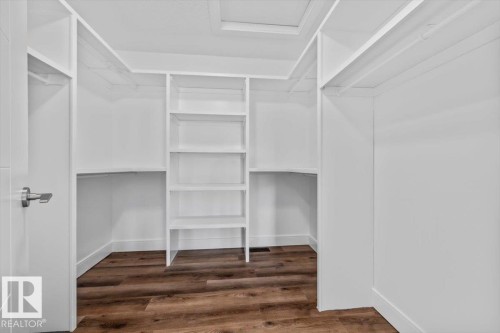 Walk-in closet with integrated shelving, multiple hanging rods, and wood-finish flooring - 1090 Armitage Crescent Sw, Edmonton, AB 