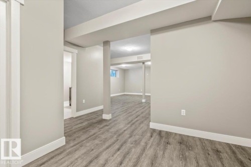 Expansive finished basement with recessed lighting, wood-finish flooring, and crisp white trim - 1090 Armitage Crescent Sw, Edmonton, AB 