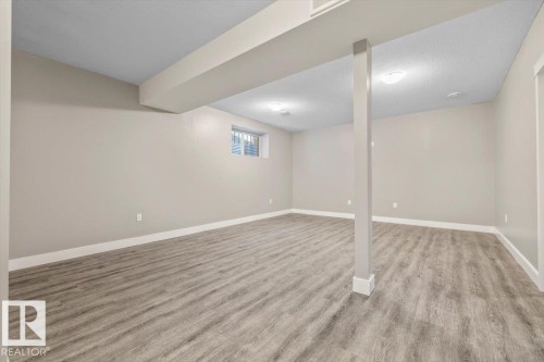 Spacious room featuring wood-finish flooring, light neutral wall tones, and recessed lighting - 1090 Armitage Crescent Sw, Edmonton, AB 