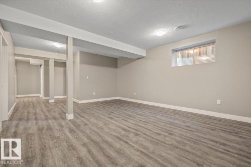 Expansive finished space with wood-finish flooring, recessed lighting, and a window - 1090 Armitage Crescent Sw, Edmonton, AB 