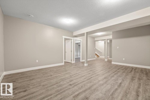 Spacious room featuring wood-finish flooring, light neutral wall paint, white trim, and recessed lighting - 1090 Armitage Crescent Sw, Edmonton, AB 