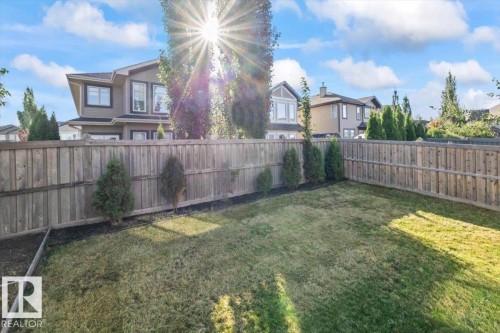 Expansive backyard featuring a partial wood fence, manicured lawn, and planted shrubs - 1090 Armitage Crescent Sw, Edmonton, AB 
